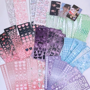 Puede incluir: Una colección de láminas de pegatinas holográficas de colores con varios diseños, incluidos corazones, mariposas, estrellas y números. Las pegatinas son perfectas para agregar un toque de brillo y fantasía a los diarios, planificadores y otros proyectos de manualidades.