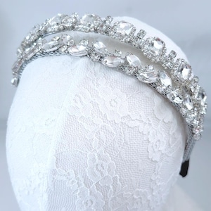 May include: A silver headband with a double row of clear rhinestones. The headband is on a white lace background.