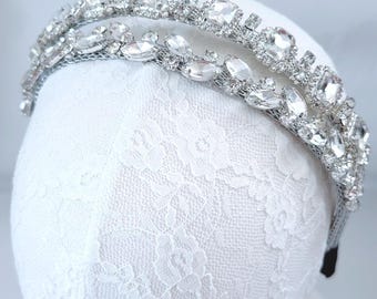 May include: A silver headband with a double row of clear rhinestones. The headband is on a white lace background.