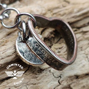 May include: A silver heart-shaped pendant made from a US quarter coin. The coin has the inscription "GEORGIA 1788" on the side. The pendant is attached to a silver chain.