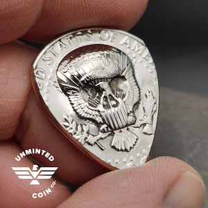 Púa de guitarra con moneda de medio dólar Kennedy estadounidense sin acuñar, con la impresión de una calavera / 1971 hasta la actualidad
