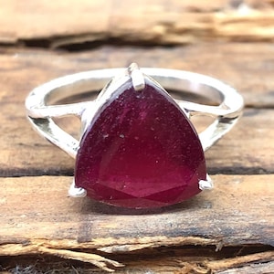 May include: A silver ring with a teardrop-shaped, deep red gemstone.