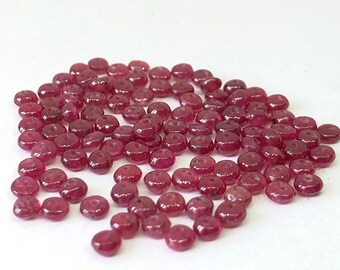 Peut inclure: Un tas de petites perles rondes de rubis rouges. Les perles sont lisses et brillantes, et elles sont toutes à peu près de la même taille.