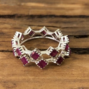 Puede incluir: Un anillo de plata con una doble fila de piedras de rubí de forma cuadrada.