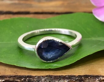May include: A silver ring with a teardrop-shaped blue gemstone.
