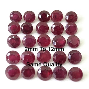 Peut inclure: Vingt-deux pierres précieuses de rubis rondes et facettées de différentes tailles, allant de 2 mm à 12 mm. Les pierres sont d'une couleur rouge foncé et ont une finition polie. "2mm To 12mm Same Quality" est écrit en blanc sur fond blanc.