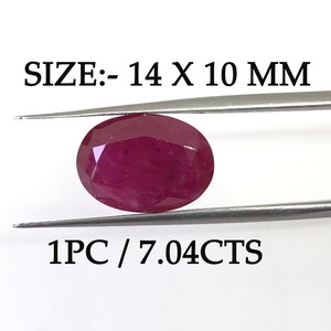 May include: A deep red oval-shaped gemstone, measuring 14 x 10 mm, held by tweezers. The gemstone weighs 7.04 carats. SIZE: - 14 X 10 MM 1PC / 7.04CTS