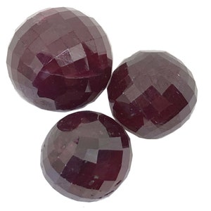 May include: Three round, faceted ruby gemstones. The gemstones are a deep red color and have a polished finish.