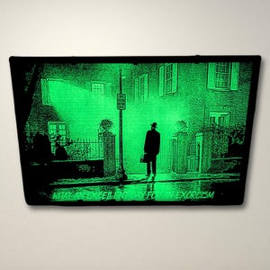 Pode incluir: Uma impress&atilde;o preta e verde que brilha no escuro de um homem caminhando por uma rua &agrave; noite. O texto "What a Excellent Day for an Exorcism" est&aacute; na parte inferior da impress&atilde;o.