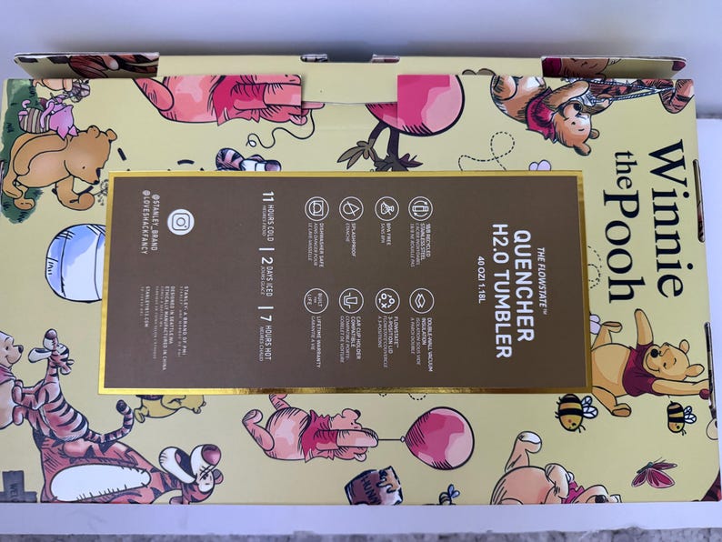 K&ouml;nnte beinhalten: Eine gelbe Box mit Winnie-the-Pooh-Figuren. Die Box enth&auml;lt einen "QUENCHER H2.0 TUMBLER" mit einem Fassungsverm&ouml;gen von 1,18 l. Die Box enth&auml;lt auch Informationen &uuml;ber die Kalt-, Eis- und Hei&szlig;haltezeiten des Tumblers.