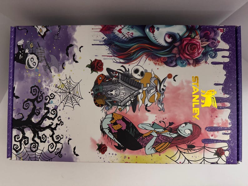 Puede incluir: Una caja rectangular con un dise&ntilde;o colorido con personajes de Pesadilla antes de Navidad. La caja tiene un borde morado y el logotipo de Stanley en dorado. La obra de arte incluye a Jack Skellington, Sally y otros elementos espeluznantes.