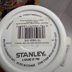 Puede incluir: Base de vaso Stanley blanca con informaci&oacute;n del producto. El texto incluye "Sin BPA", "Apto para lavavajillas" y "No microondas". El c&oacute;digo de barras es visible, junto con la marca "Stanley".