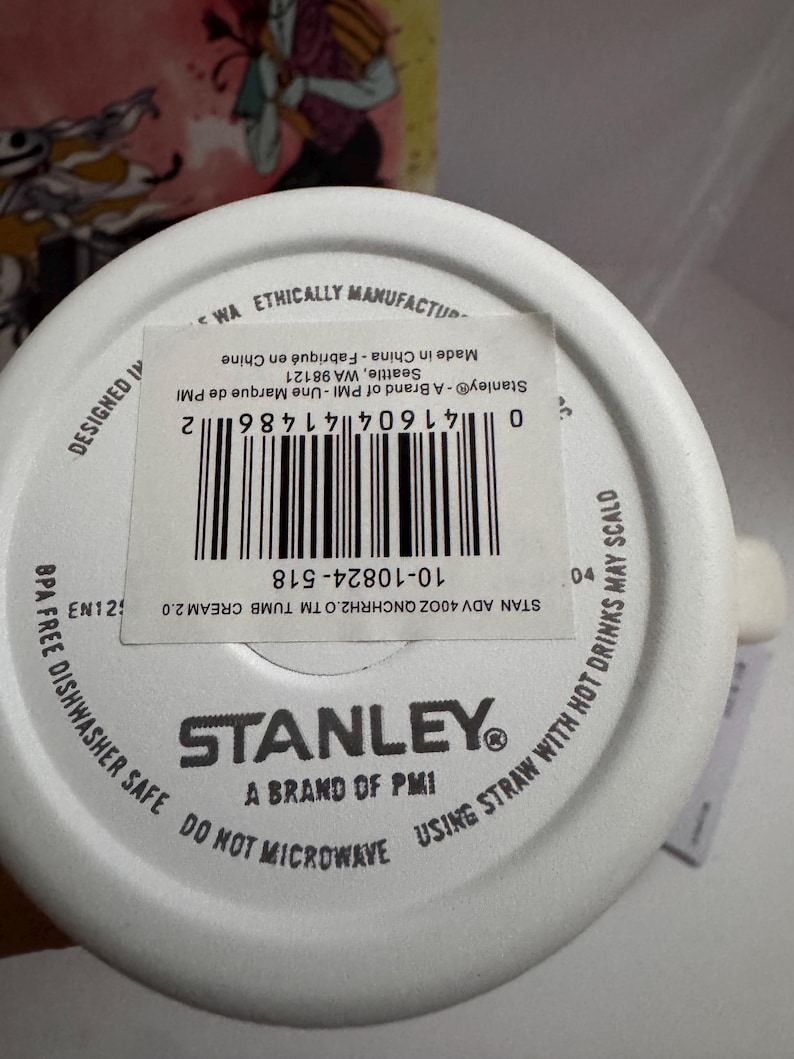 Puede incluir: Base de vaso Stanley blanca con informaci&oacute;n del producto. El texto incluye "Sin BPA", "Apto para lavavajillas" y "No microondas". El c&oacute;digo de barras es visible, junto con la marca "Stanley".