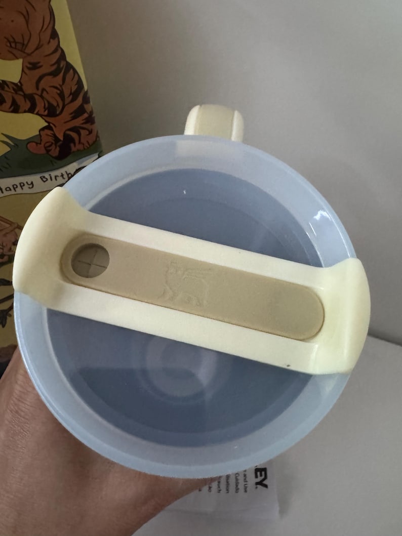 K&ouml;nnte beinhalten: Hellblaue Stanley-Thermoskanne mit cremefarbenem Griff und Deckel. Der Deckel hat einen cremefarbenen Verschluss mit dem Stanley-Logo. Die Thermoskanne h&auml;lt Getr&auml;nke hei&szlig; oder kalt.