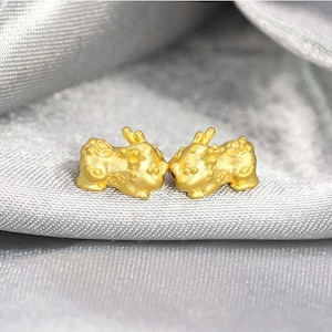 May include: Two gold-coloured, detailed, three-dimensional animal figurines. The figurines are facing each other and appear to be made of metal.