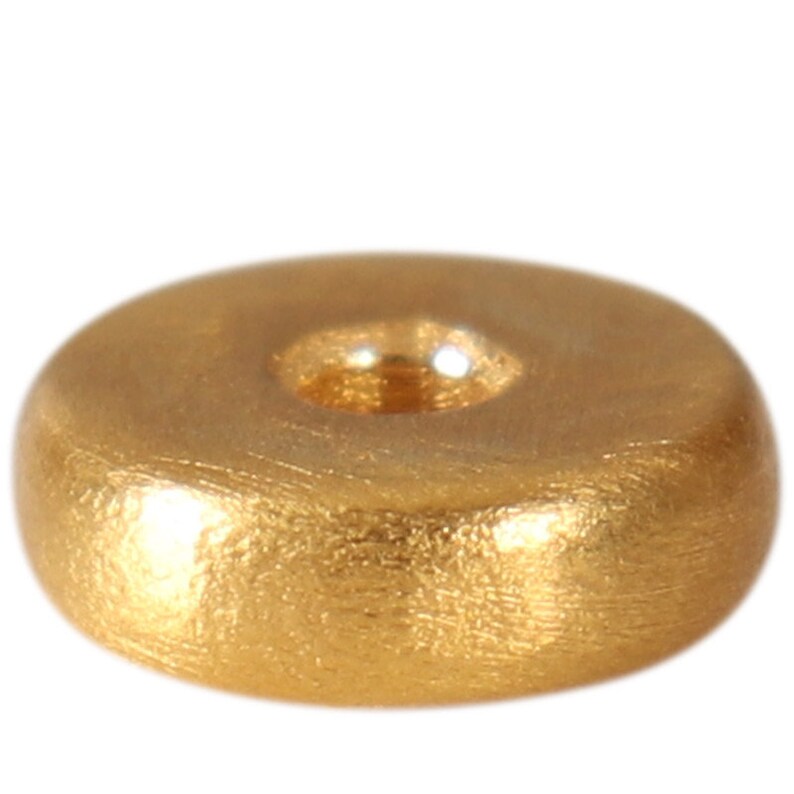 May include: A gold-colored metal bead with a round shape and a hole in the center. The bead has a textured surface.
