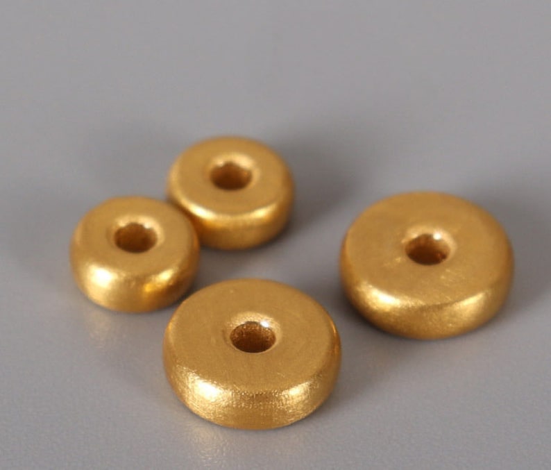May include: Four gold-colored wooden beads with a hole in the center. The beads are round and have a smooth, shiny finish.