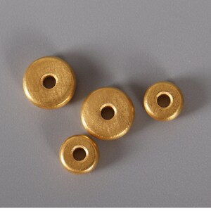 May include: Four gold-colored wooden beads with a hole in the center. The beads are round and have a smooth surface.