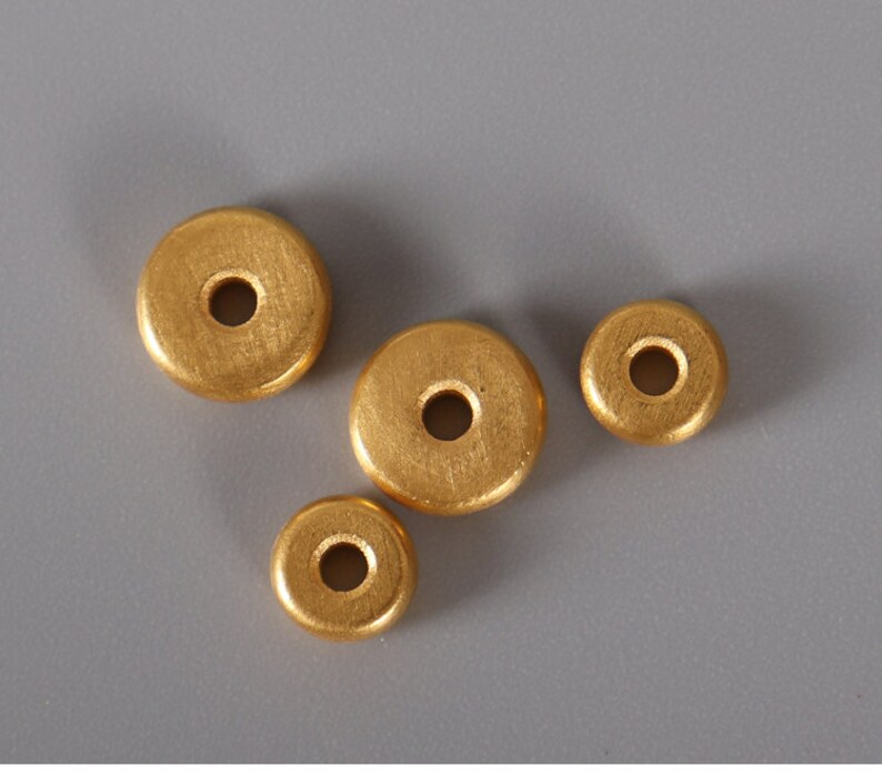 May include: Four gold-colored wooden beads with a hole in the center. The beads are round and have a smooth surface.