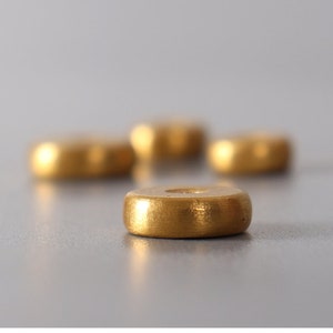 May include: Four gold-colored round incense burner holders. The holders are stacked on top of each other, with the top holder in focus.