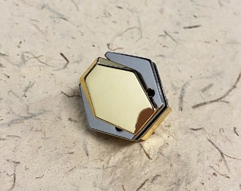 May include: A gold hexagonal shaped object with a silver frame. The object is made of metal and has a shiny finish.