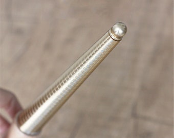 Può includere: Un misuratore di misura per anelli in metallo dorato con una serie di anelli graduati. Il misuratore è progettato per aiutare a determinare la misura dell'anello corretta.