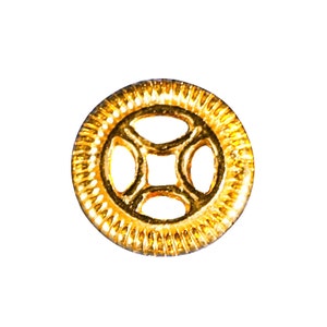 May include: A gold-colored metal button with a decorative design featuring four overlapping circles. The button has a textured outer edge.