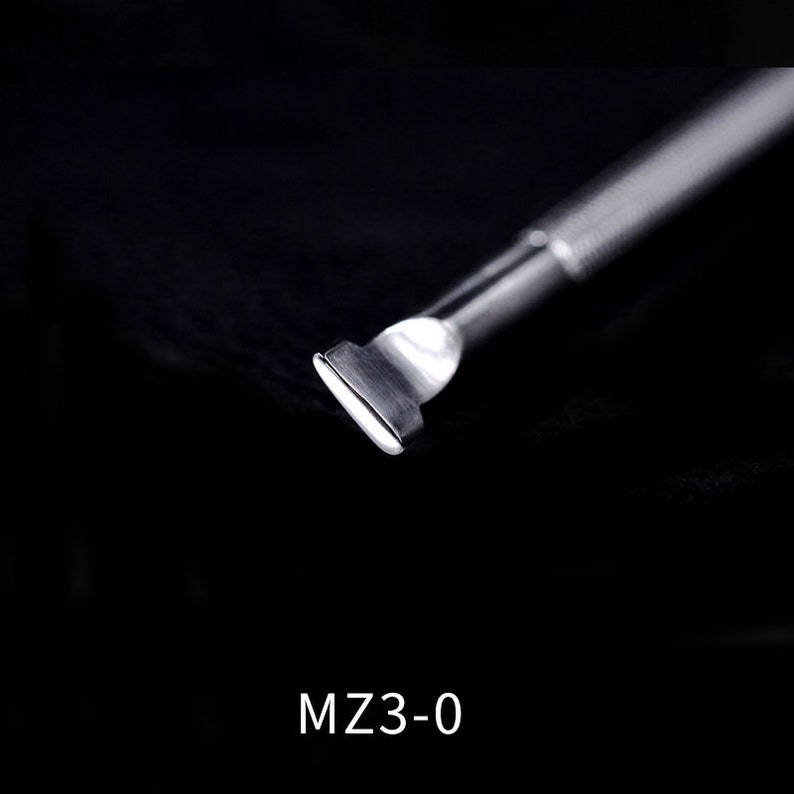 Pu&ograve; includere: Uno strumento in metallo argentato per spingere le cuticole, con una punta arrotondata. Lo strumento &egrave; su uno sfondo nero. MZ3-0