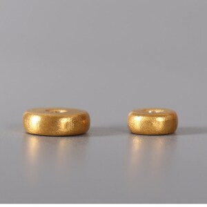 May include: Two gold-colored metal incense holders, one larger than the other, are shown on a gray background.
