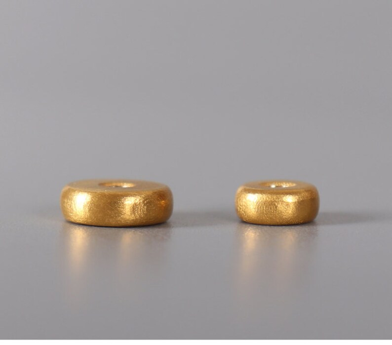 May include: Two gold-colored metal incense holders, one larger than the other, are shown on a gray background.