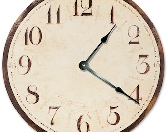 May include: A round wall clock with a cream-colored face and dark brown, distressed-style numerals from 1 to 12. The clock features a dark brown outer rim, black metal hour and minute hands, and small decorative markings at the 15, 30, 45, and 60-minute positions.
