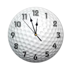 May include: A white golf ball clock with black numbers and hands. The clock face is designed to look like a golf ball with dimples.