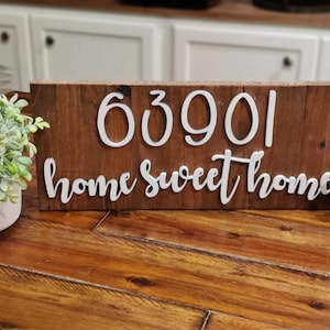 May include: A wooden sign with the house number 63901 and the text "home sweet home" in white raised letters.