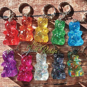 May include: A collection of colorful gummy bear keychains in various colors, including red, orange, yellow, green, blue, purple, pink, clear, black, and a mix of colors. Each bear is attached to a silver keyring.