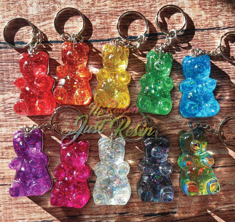 May include: A collection of colorful gummy bear keychains in various colors, including red, orange, yellow, green, blue, purple, pink, clear, black, and a mix of colors. Each bear is attached to a silver keyring.