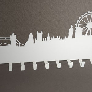 Puede incluir: Porta llaves de metal blanco con el horizonte de Londres y 8 ganchos. El horizonte incluye el Tower Bridge, Big Ben y el London Eye.