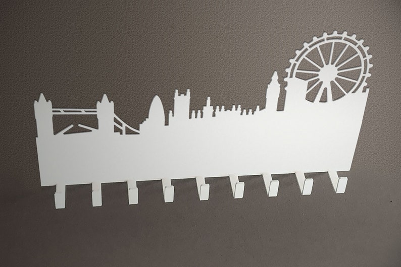 Puede incluir: Porta llaves de metal blanco con el horizonte de Londres y 8 ganchos. El horizonte incluye el Tower Bridge, Big Ben y el London Eye.