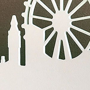 Puede incluir: Corte de papel blanco del horizonte de Londres con la noria London Eye en el fondo.