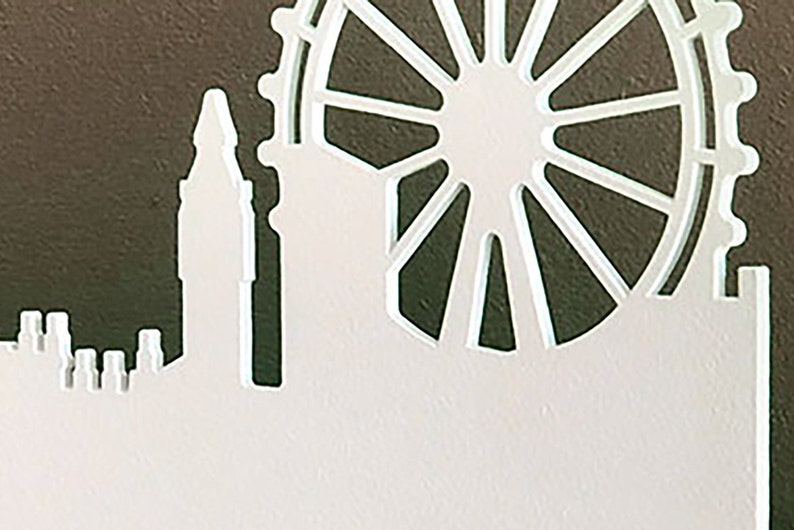 Puede incluir: Corte de papel blanco del horizonte de Londres con la noria London Eye en el fondo.