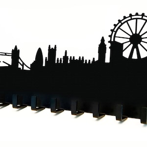 Puede incluir: Porta llaves de metal negro con forma de horizonte de Londres, con el London Eye, el Big Ben y el Tower Bridge. El soporte tiene ocho ganchos para colgar llaves.