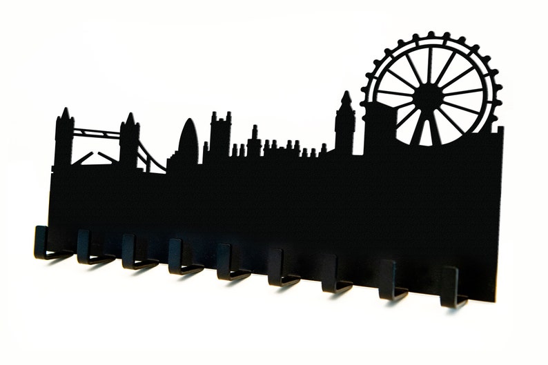 Puede incluir: Porta llaves de metal negro con forma de horizonte de Londres, con el London Eye, el Big Ben y el Tower Bridge. El soporte tiene ocho ganchos para colgar llaves.
