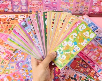 Puede incluir: Una gran colección de hojas de pegatinas coloridas con adorables animales de dibujos animados, comida y otros diseños. Las pegatinas están dispuestas en forma de abanico y están listas para usarse para decorar diarios, planificadores y otros artículos.