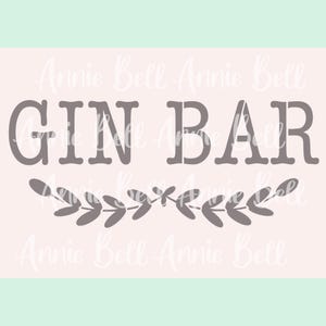 May include: A light pink sign with the words "GIN BAR" in gray, stylized block letters. Below the text is a gray leaf garland. The background has a light green border at the bottom and the words "Annie Bell" repeated in a light color.