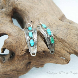May include: Two vintage silver watch straps with turquoise and green stone accents. Each strap features three turquoise stones and one green stone, set in a decorative silver band. The straps are displayed on a piece of driftwood.