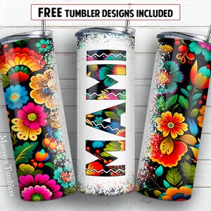May include: Three stainless steel tumblers with different designs. One tumbler features a colourful floral pattern on a black background. Another tumbler has the word "MAM" in a colourful, stylised font. The third tumbler has a similar floral pattern to the first tumbler. The tumblers are all on a white wooden background.