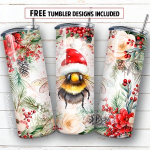 Puede incluir: Tres vasos de acero inoxidable con temática navideña. Los vasos presentan un diseño de acuarela de una abeja con un gorro de Papá Noel, bayas rojas, ramas de pino y flores blancas. El texto "Mamaya Tumblers" está en el vaso de la izquierda.