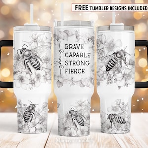 Può includere: Un bicchiere in acciaio inossidabile bianco con manico e coperchio neri. Il bicchiere presenta un'illustrazione in bianco e nero di un'ape e fiori con il testo "She is Brave Capable Strong Fierce".