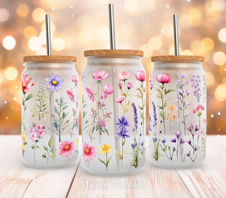 May include: Three clear glass tumblers with wooden lids and stainless steel straws. Each tumbler features a different floral design with pink, purple, and yellow flowers.