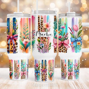 May include: Three stainless steel tumblers with colorful floral and animal print designs. The tumblers have lids and straws. The middle tumbler has the word "Mama" printed on it.