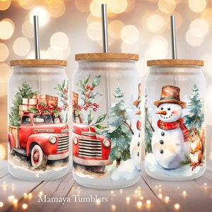 Puede incluir: Tres vasos temáticos de Navidad con tapas y pajitas. El primer vaso presenta un camión vintage rojo con un árbol de Navidad y regalos en la parte trasera. El segundo vaso presenta una escena de invierno con un muñeco de nieve y un pino. El tercer vaso presenta un muñeco de nieve con una bufanda roja y negra y una ardilla.